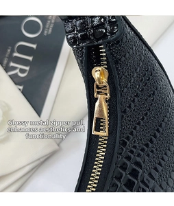 Close-up of black crocodile pattern leather texture with glossy gold metal zipper detail