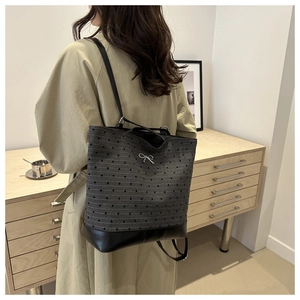 Detail of dark gray knit tote bag with silver bow accent and leather base on model