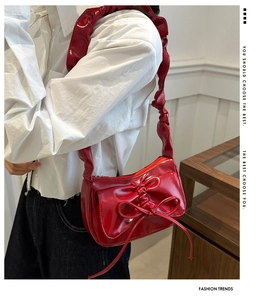 Detail of red patent leather shoulder bag with chic 3D bow and scrunchie strap design