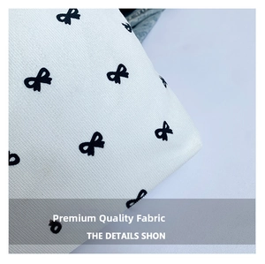 Close-up of durable canvas fabric with elegant black bow pattern on white material
