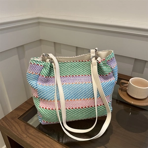 Colorful woven tote bag with white leather straps on a cafe table for daily commuting
