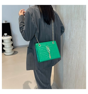 Détail du sac à bandoulière vert croco brillant avec chaîne dorée et logo S