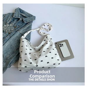 Close-up of white canvas tote bag with black bow patterns and textured fabric detail