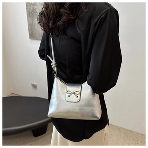 Détail d'un sac argenté métallisé avec ornement de nœud et bandoulière nouée