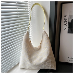 Detailed close-up of the woven texture and lemon yellow strap on a cream tote bag