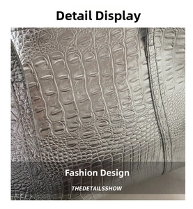 Detailed close-up of grey crocodile embossed leather texture and fine stitching on the bag