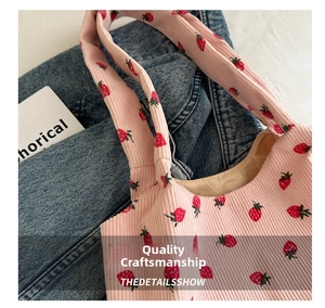 Close-up of pink corduroy tote bag featuring red strawberry patterns and soft texture