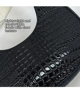 Detail of black faux crocodile leather shoulder bag showing glossy embossed texture