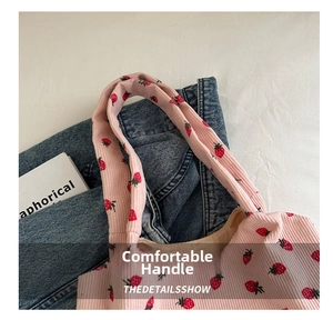 Detail of soft corduroy handle with strawberry prints on a pink tote handbag