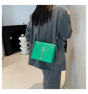 Détail du sac vert vif en cuir embossé crocodile avec pompon doré et chaîne élégante