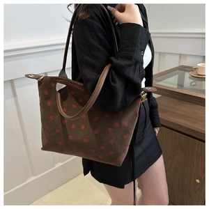 Detail of strawberry print corduroy tote bag showing leather handles and texture