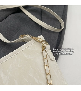 Close-up of white marble textured leather bag with gold hardware and chain detail