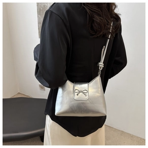 Sac seau argenté avec fermoir nœud métallique et détail de bandoulière nouée sur modèle