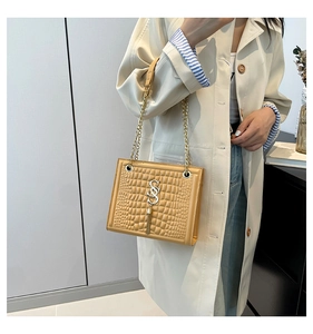 Détail du sac bandoulière jaune embossé crocodile avec pompon doré et bandoulière chaîne