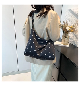 Detailed back view of a large black canvas tote bag with white bow pattern prints