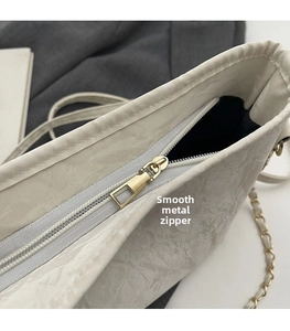 Detail of smooth gold zipper and marble texture on light gray commuter bucket bag