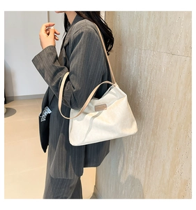 Close-up of beige textured fabric shoulder bag with leather strap on a model's arm