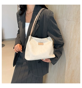 Close-up of cream corduroy tote bag featuring leather patch and dual shoulder straps