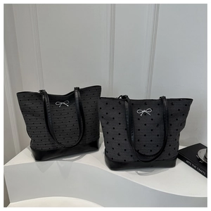 Detailed view of two grey polka dot tote bags with black leather base and bow charms