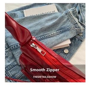 Detailed macro view of the high-shine silver metal zipper on a red faux leather handbag