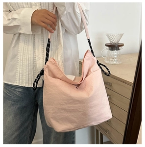 Détail du sac fourre-tout en nylon rose clair avec bandoulière en corde tressée bicolore