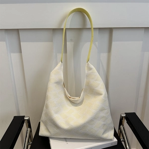 Chic woven cream tote bag with yellow shoulder strap and textured minimalist design