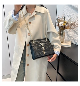 Détail du sac noir texture crocodile avec chaîne dorée et pompon logo S chic