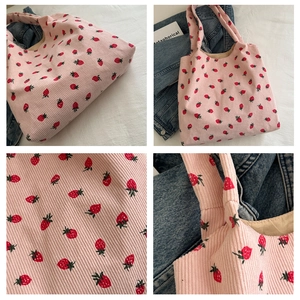 Detail view of pink corduroy tote bag featuring red strawberry patterns and fine stitching