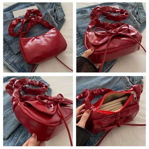 Detailed views of red glossy leather crescent bag with bow decoration and scrunchie strap
