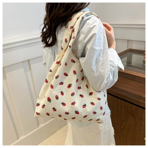 Detail of strawberry embroidery on corduroy tote bag showing textured craftsmanship