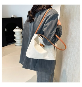 Detailed view of white textured tote bag with contrast tan straps on model's shoulder