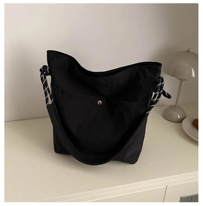 Détail d'un sac seau minimaliste en nylon noir avec des poignées en corde bicolore et bouton