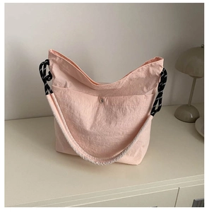 Détail macro du sac en nylon pêche avec bandoulière tissée et fermoir magnétique