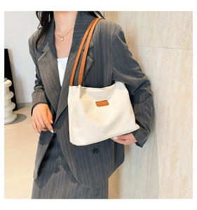 Detailed texture of white corduroy shoulder bag with brown leather strap on model
