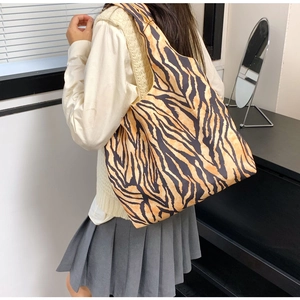 Detail of spacious tiger print canvas tote bag carried by model in indoor setting