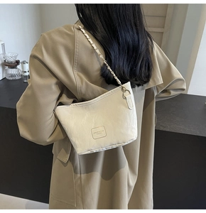Detail of off-white trapezoid bucket bag with metallic chain strap and textured fabric