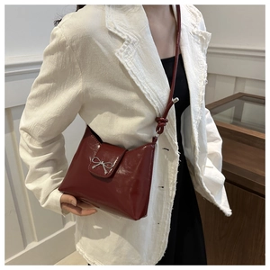 Gros plan sur un sac rouge bordeaux brillant avec nœud argenté et bandoulière nouée