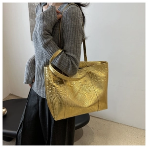 Close-up of the large tote bag showing gold crocodile texture and handle detail