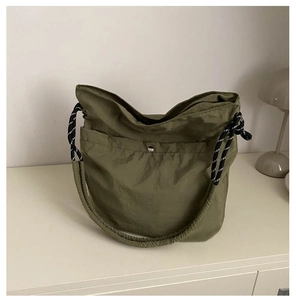 Détail du sac seau en nylon vert olive avec bandoulière tissée et fermeture à bouton pression