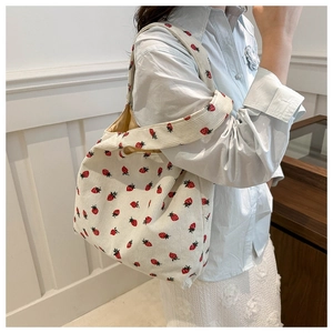 Detail of corduroy tote bag featuring red strawberry prints and soft knitted texture