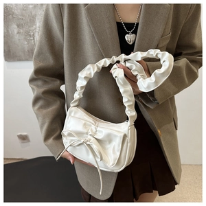 Close-up of a white glossy underarm bag with a stylish bow and ruched handle design