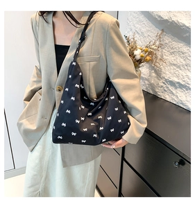 Close-up of black oversized shoulder bag featuring white bow patterns and soft texture
