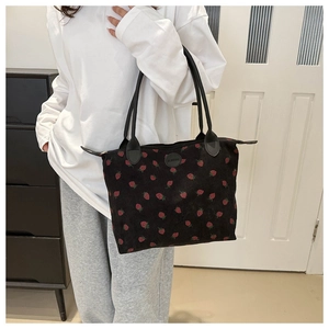 Detail of strawberry print on black corduroy tote bag with zipper and slim shoulder strap
