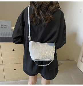 Detail of grey pleated bucket bag with gold chain strap and square metal plate