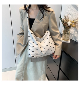 Detail of white canvas hobo bag with black bow print and comfortable wide shoulder strap
