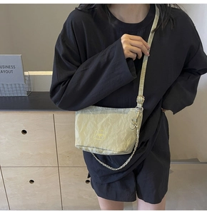 Detail of light green bucket bag showing pleated fabric texture and silver chain strap