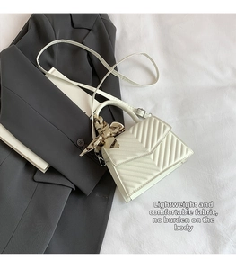 Detail of cream crossbody bag with V-shaped stitching and floral silk scarf handle