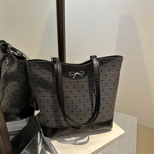 Polka dot canvas tote bag with black leather handles and silver bow metal detail