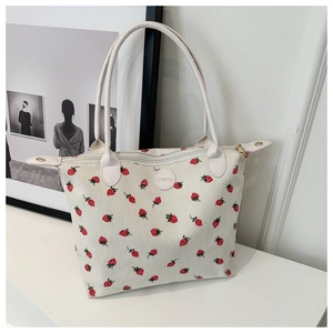 Detail of corduroy tote bag with strawberry print and leather logo patch with zipper