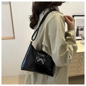 Détail du sac sous l'aisselle en cuir noir avec boucle noeud argenté à l'épaule